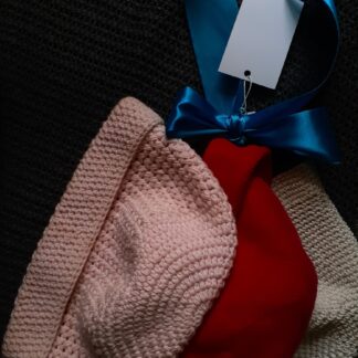 three knitted hats with a blue ribbon around them